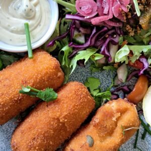 Enjoy crispy fish croquettes paired with a vibrant salad and tangy sauce.