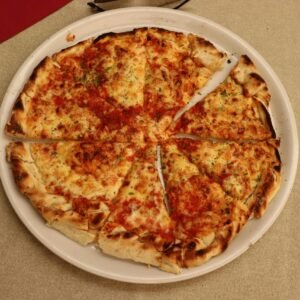 Savor a freshly baked traditional pizza captured in Kotor, highlighting its cheesy, crispy perfection.